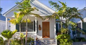 Beautiful white Key West Cottage with palm trees and a brown door