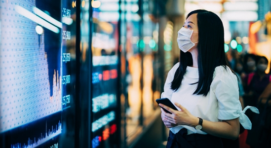 Woman with a mask on reading information off of monitor.