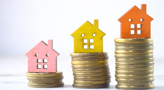 Small wooden houses on stacks of coins