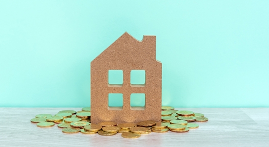 Wooden house with gold coins on table