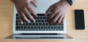 Overhead view of man typing on laptop keyboard.